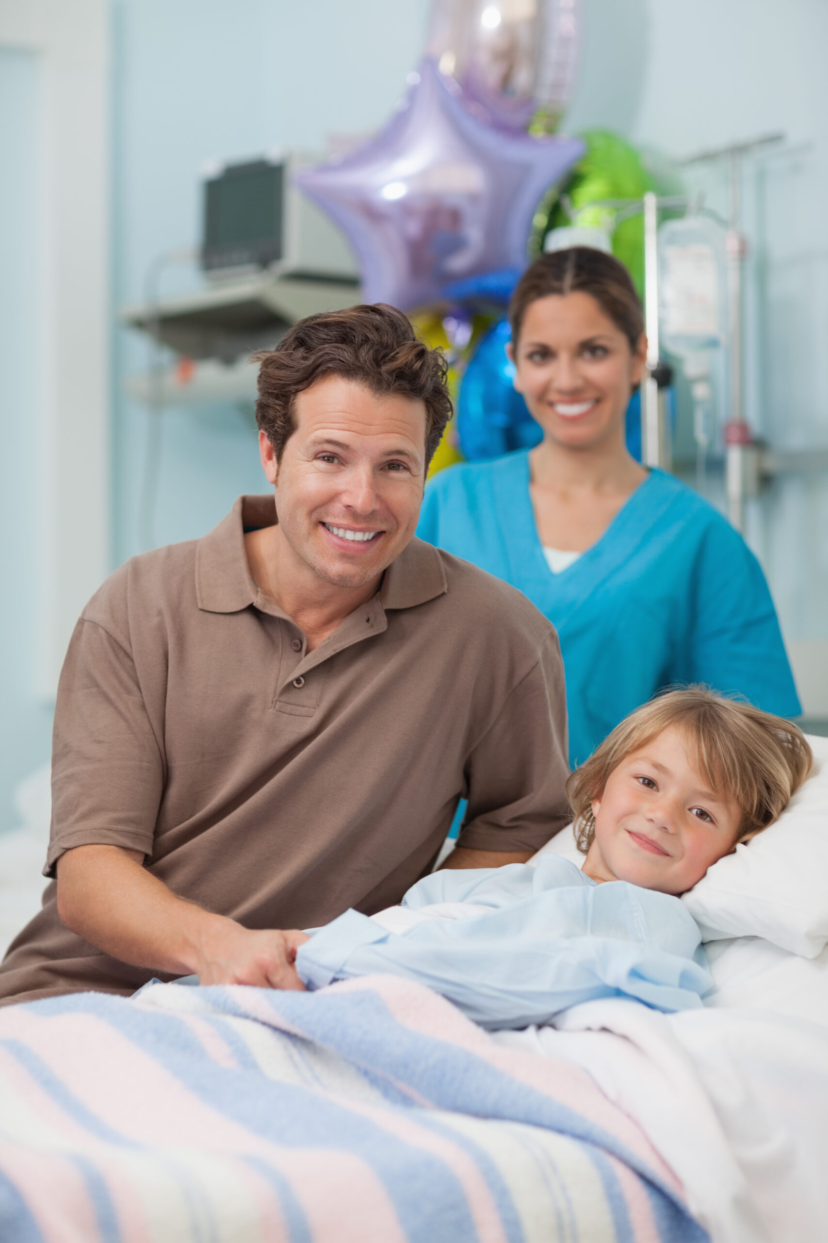 Child and his father looking at camera in hospital ward